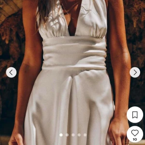 Vit halterneck  klänning - Säljer en jätte fin vit halterneck klänning i satin med djup v-ringning. Perfekt nu inför student eller skolavslutning! Använd endast en gång! Den har även en fin knytning i ryggen (bild 4)🩷🩷