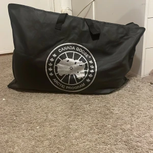 Svart parkajacka från Canada Goose - ÄKTA!! Säljer en svart parkajacka från Canada Goose med pälsdetalj på huvan. Jackan har en broderad logotyp på bröstet och är perfekt för kalla dagar. Den är tillverkad i Kanada och har en klassisk design med långa ärmar och dragkedja. Köpte den för 12 000 men säljer den för 2500🤍🖤