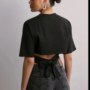 Svart kortärmad topp med knyt - Snygg svart topp med korta ärmar och knytning i ryggen. Perfekt för en stilren look med en twist. Skriv innan köp och tar bara Swish då Plick inte fungerar så bra 