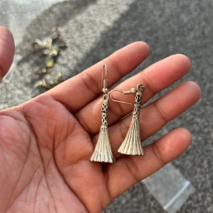 Silvriga örhängen med fransdetalj - Snygga silvriga örhängen med en unik fransdesign. De har en elegant och detaljerad topp som övergår i en bredare fransliknande form. Perfekta för att ge en stilfull touch till din outfit.