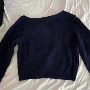 Mörkblå stickad tröja - Säljer en mörkblå stickad tröja med långärmad design. Perfekt för kyligare dagar med sin mysiga och varma känsla. Tröjan har en enkel och stilren look.