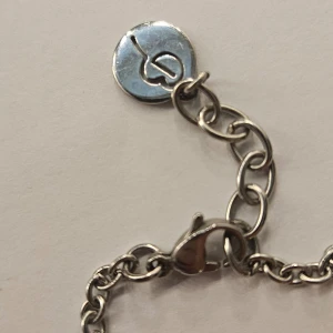 Silverfärgat armband med cirkeldetaljer - Snyggt silverfärgat armband med två cirkelformade hängen, varav ett är dekorerat med glittrande stenar. Armbandet har en klassisk kedja och en säker låsning. Perfekt för att ge en elegant touch till din outfit.