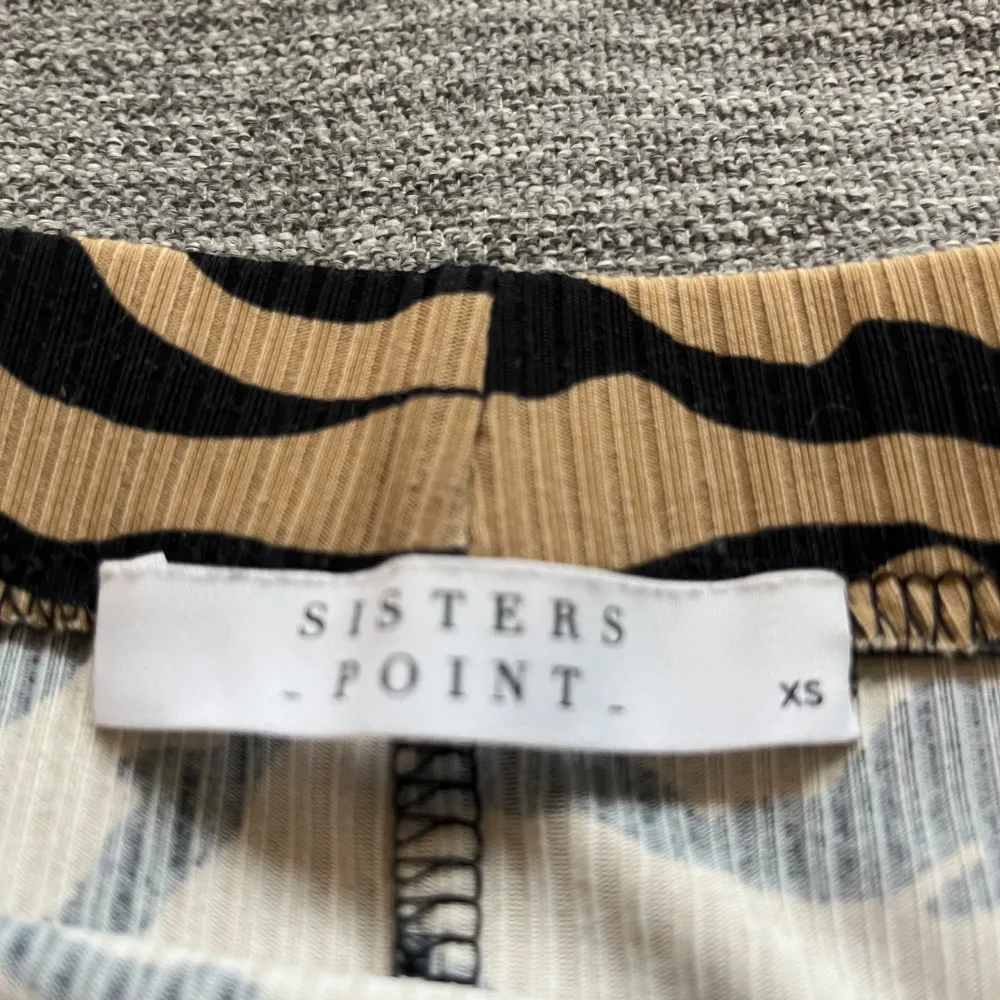 Snygg zebramönstrad kjol från Sisters Point i beige och svart. Kjolen har en tight passform och är perfekt för att sticka ut med sitt djärva mönster. Den är gjord i ett mjukt och bekvämt material som passar bra till olika tillfällen.. Hameet.