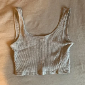 Beige ribbad linnetopp från Gina Tricot - Säljer ett superfint croppat grått ribbat linne från Gina Tricot. Toppen är i storlek XS och har bara använt fåtal gånger. 