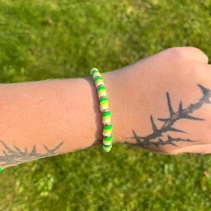 Färgglatt pärlarmband - Säljer ett supercoolt armband med pärlor i grönt, gult och vitt. Perfekt för att liva upp vilken outfit som helst! Armbandet är elastiskt och passar de flesta handleder. Perfekt accessoar för sommarens alla äventyr! 🌞
