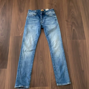 Blå jeans från Jack & Jones - Säljer ett par snygga blå jeans från Jack & Jones. De har en slim fit och är i modellen Glenn. Jeansen har en klassisk femficksdesign och är tillverkade i ett slitstarkt denimtyg. Perfekta för både vardag och fest!