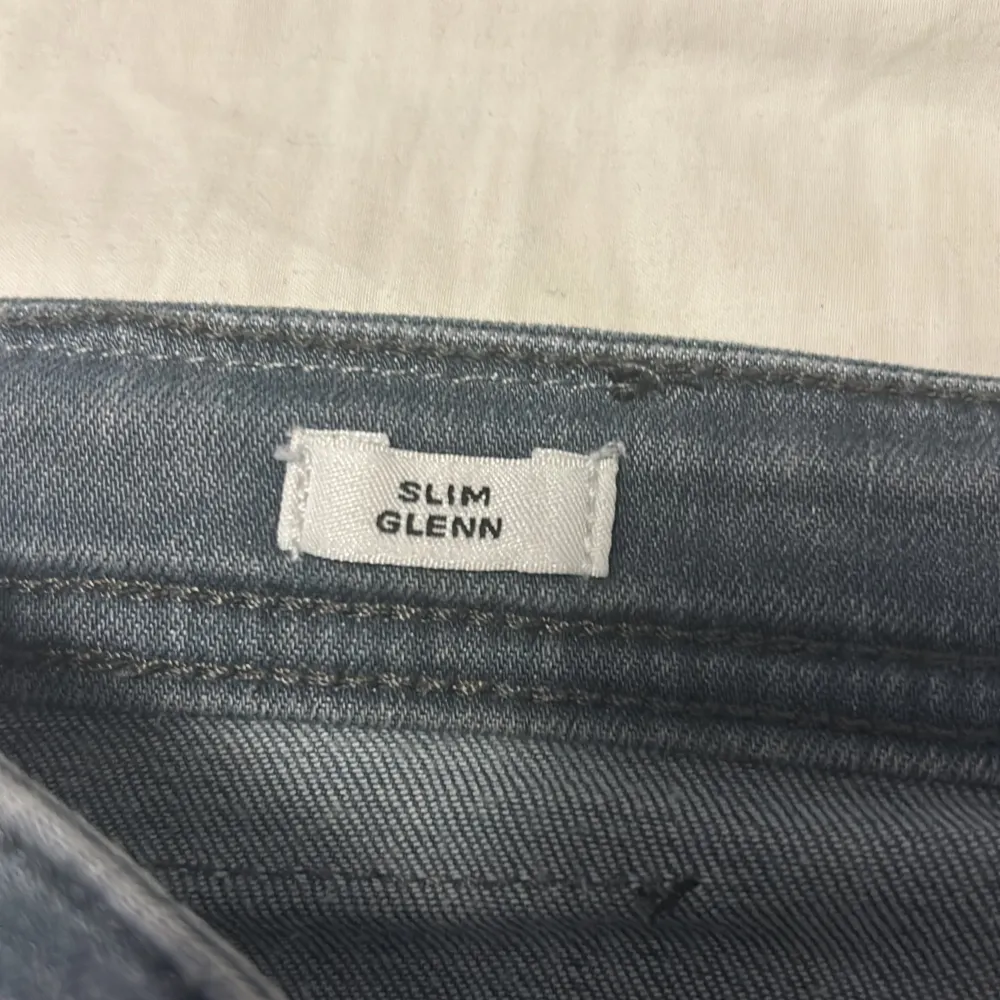 Säljer ett par grå jeans i modellen Slim Glenn. De är i storlek 176/16Y och har en slim passform. Perfekta för en stilren och bekväm look!. Jeans & Byxor.