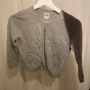 Grå kofta från Little Coats - Säljer en söt och enkel grå kofta / bolero från soft goat. Den har knappar framtill och är perfekt för både vardag och lite kyligare dagar. Koftan är i ett mjukt material (kashmir.) 