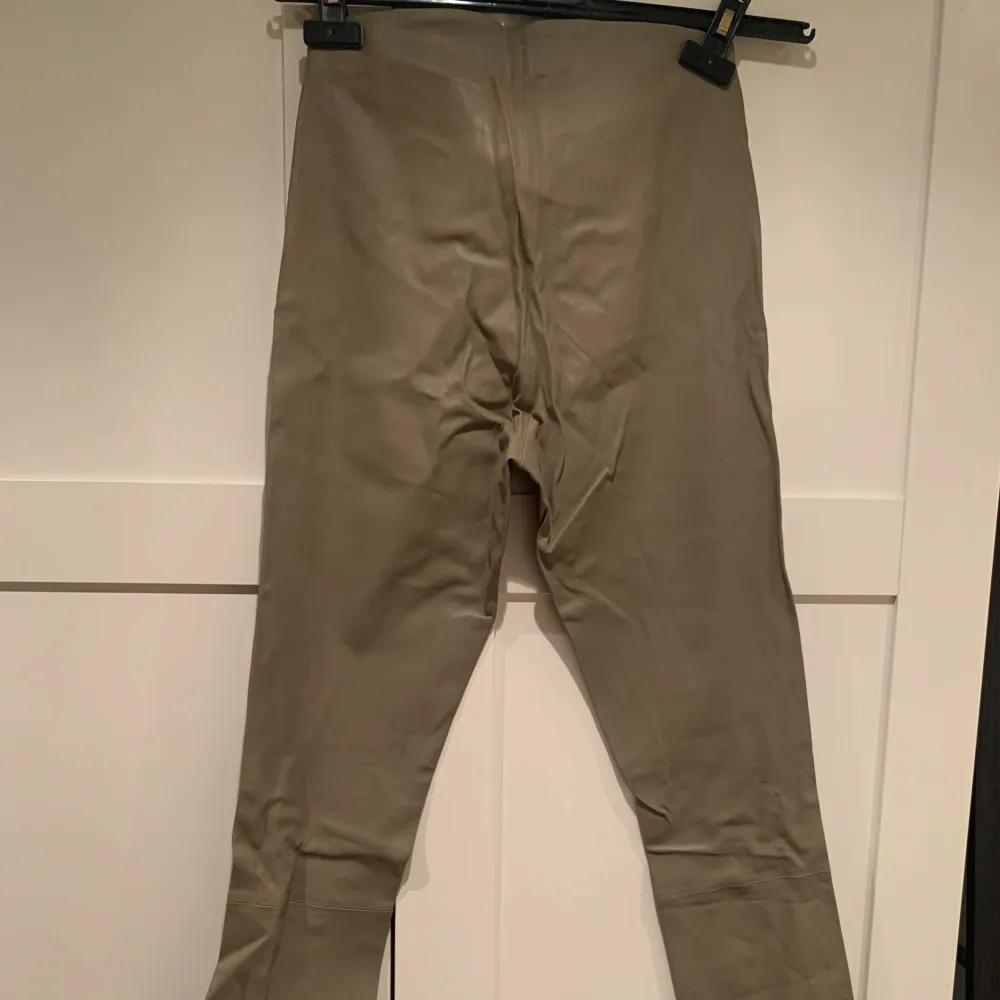 Snygga beige skinnbyxor från By Malene Birger i 100% fårskinn. Byxorna har en stilren design med en tight passform som ger en elegant look. Perfekta för att lyfta vilken outfit som helst med en touch av lyx.Modellen är Elenasoo . Farkut & Housut.