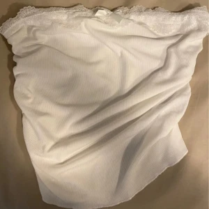 Vit top från Shein - Säljer en söt vit top från Shein med spetsdetaljer och en liten rosett. Toppen har en ribbad struktur och är perfekt för en romantisk look. 