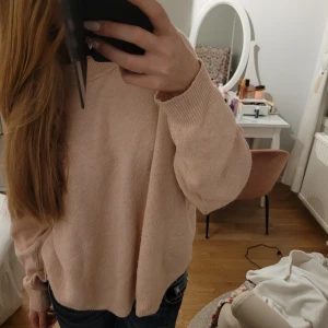 Beige/rosa stickad tröja från H&M - Säljer en mysig rosa stickad tröja från H&M. Tröjan har en avslappnad passform med långa ärmar och ribbade muddar. Perfekt för kyligare dagar. 