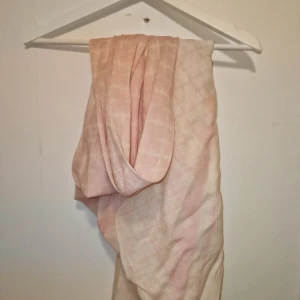 Rosa halsduk från By Malene Birger - Säljer en elegant rosa halsduk från By Malene Birger. Den är tillverkad i 100% ull och har ett subtilt mönster som ger en lyxig känsla. Perfekt för att hålla dig varm och stilren under kyliga dagar. Garderobsrensning så kika gärna in övriga auktioner ✨️
