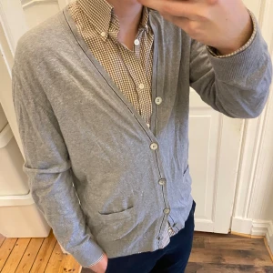 Grå cardigan från Marc O'Polo - Säljer en stilren grå cardigan från Marc O'Polo i en mjuk blandning av pima bomull och kashmir. Koftan har knappar framtill och två praktiska fickor. Perfekt för lager-på-lager stil. Den är ganska skrynklig men går att fixa lätt. Jag brukar ha S/M men denna är L. Tveka inte att kontakta vid eventuella frågor 😀