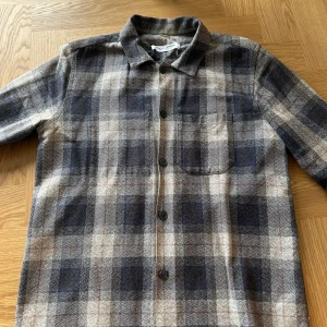 Rutig overshirt från Samsøe Samsøe - Snygg rutig overshirt från Samsøe Samsøe i jordnära färger. Skjortan har långa ärmar och knappar framtill. Perfekt för lager-på-lager-stil under kyligare dagar.