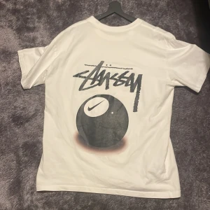 Vit t-shirt  Stüssy x Nike - Vit t-shirt med tryck från Stüssy x Nike. Den har ett stort grafiskt tryck på baksidan och ett mindre på framsidan. Helt okej skick 7/10 