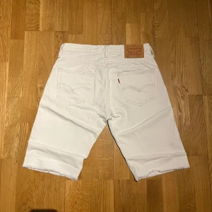 Vita jeansshorts från Levi's - Snygga vita jeansshorts från Levi's modell 501. Klassisk design med fem fickor och knappgylf. Perfekta för en avslappnad stil.