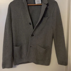 Stickad cardigan  Zara - Snygg grå stickad cardigan från Zara med klassisk design.
