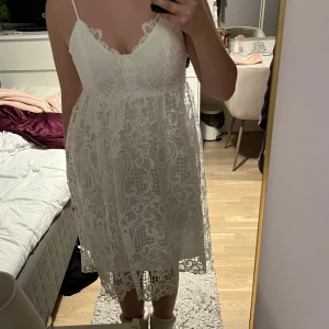 Vit spetsklänning från Vila - Säljer en vacker vit spetsklänning från Vila med smala axelband och v-ringad design. Klänningen har ett fint spetsmönster och når till knäna, perfekt för sommarens festligheter. Den har en romantisk och luftig känsla som gör den idealisk för varma dagar. Endast använd en gång, helt i nyskick! Perfekt för studenten eller skolavslutning. 😻🌻.                                                      Öppen för prisförslag. ☺️