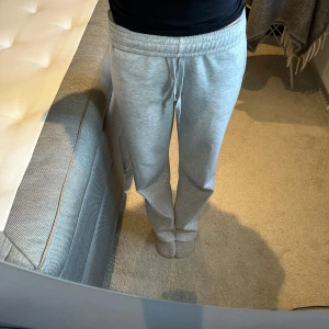 Grå mjukisbyxor från Gina tricot - Säljer ett par bekväma grå mjukisbyxor med snörning i midjan. Perfekta för en avslappnad dag hemma eller en snabb tur till affären. Byxorna har en loose passform och är gjorda i mjukt material för extra komfort.