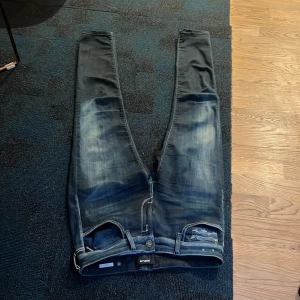 Mörkblå jeans från Replay - Säljer ett par mörkblå jeans från Replay med snygga slitningar och klassisk femficksdesign. Jeansen har en normal passform och är perfekta för en avslappnad stil. Märkeslogga på insidan av midjan och kontrastsömmar på bakfickorna. Tyvärr så finns det en liten defekt vid högra bakfick men man kan se den som en snygg slitning. Defekten är väldigt liten ungefär lite mindre en än en krona. Har du några frågor så är det bara att fråga pris kan diskuteras 😁🙌