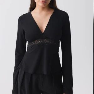 Svart långärmad topp med spetsdetalj - Snygg svart långärmad topp med v-ringning och spetsdetalj under bysten. Perfekt för en stilren look. Endast testad!🌸xxs/xs