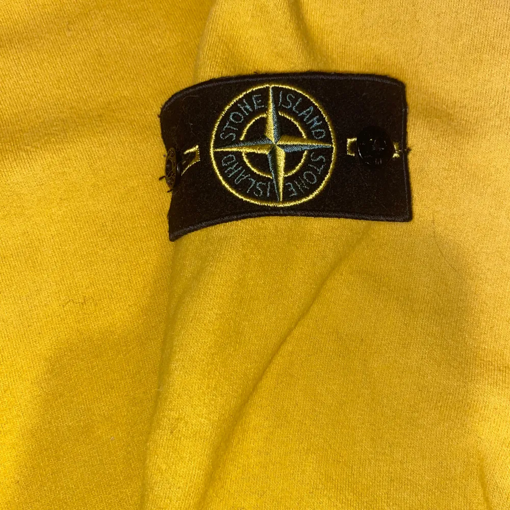 Säljer en snygg gul tröja från Stone Island med deras ikoniska märke på ärmen. Tröjan har en klassisk rund hals och långa ärmar, perfekt för en stilren look. Skriv ett PM för frågor, bilder etc (priset är ej skrivet i sten) f . Neuletakit & Villapaidat.