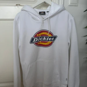 Vit hoodie från Dickies - Säljer en vit hoodie från Dickies med deras ikoniska logga i rött och gult på bröstet. Säljer den då jag bara använt den 1 gång (tvättad 1 gång). Var inte riktigt min stil. 