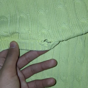 Gul stickad tröja från Ralph Lauren - Säljer en gul stickad tröja från Ralph Lauren med kabelstickat mönster. Tröjan har korta ärmar och en liten blå logga på bröstet. Perfekt för en stilren look!