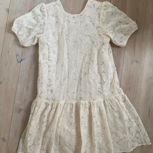 Klänning med blomspets  - Säljer min fina konkarklänning, strl 164. Endast använd 1 gång, på min konfirmation. Har en superfin V-ringning i bak, cremevit och från boozt, nyskick 600 kr