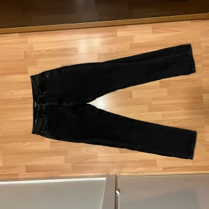 Jack and jones jeans - Snygga svarta jeansbyxor med relaxed/chris design. De har en rak passform och är tillverkade i ett slitstarkt material. Byxorna har en dragkedja och knapp framtill samt fickor både fram och bak. Perfekta för en stilren look. Enda defekten är lite slitage på baksidan av båda ben (se sista bild). 