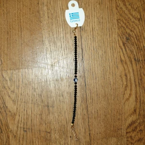 Mörkblå armband med öga - Elegant svart armband med små pärlor och ett dekorativt öga i mitten. Perfekt för att ge en stilren touch till din outfit. Tillverkat i Grekland.