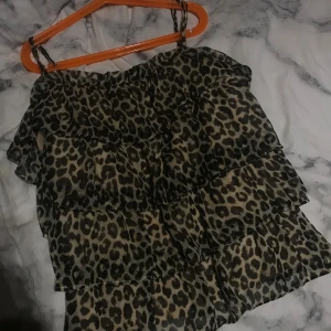 Leopardmönstrad offshoulder-top - Trendig offshoulder-top med leopardmönster och volanger. Perfekt för en djärv look.från Vera Moda 