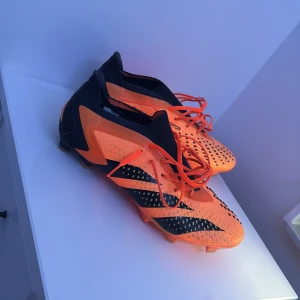  Adidas accuracy.1 orange elite  - Säljer ett par iögonfallande orange och svarta Adidas fotbollsskor med snörning. Skorna har en modern design med svarta detaljer och är perfekta för fotbollsplanen. De är tillverkade i syntetmaterial för optimal prestanda. Säljer dem på grund av att jag köpt nya och dem är som nya 