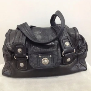 Marc jacobs väska - Snygg svart skinnväska från Marc Jacobs med silver detaljer. Väskan är rymlig och har ett innerfack med dragkedja samt två mindre fack inne. Bredd-34 cm, Höjd- 21 cm , Djup- 17 cm, Band- 70 cm