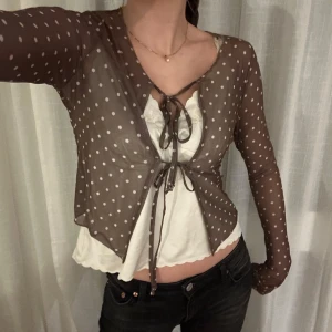 Brun prickig bolerotopp - En tunn brun bolerotopp med vita prickar och knytning framtill från Motel rocks. Endast testad. 