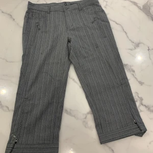 Randiga byxor från Bison - Snygga grå randiga byxor från Bison med dragkedjedetaljer. Tillverkade i en bekväm blandning av polyester, viskos och elastan. 