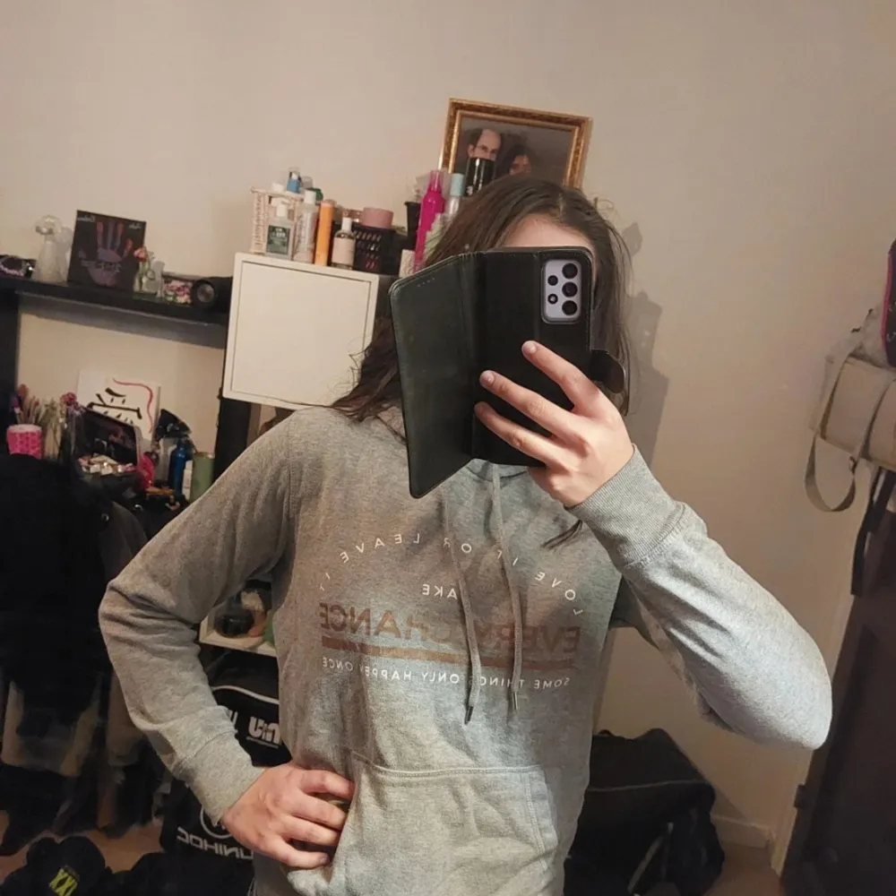 Säljer en grå hoodie med tryck framtill. Den har en klassisk design med huva och långa ärmar. Perfekt för en avslappnad stil.. Neuletakit & Villapaidat.