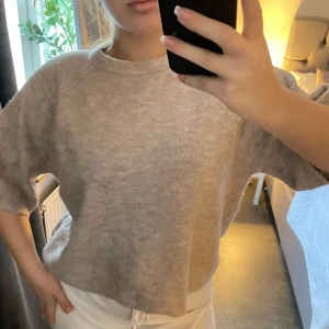 Grå lila  stickad tröja - Mysig grå lila  stickad tröja med korta ärmar. Perfekt för en avslappnad stil. Tröjan har en rund hals och en lös passform som ger en bekväm känsla.