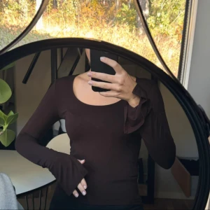 Brun långärmad topp - Snygg brun långärmad topp med rund halsringning. Perfekt för en stilren look och passar bra till både jeans och kjol. Toppen har en tight passform som framhäver figuren.
