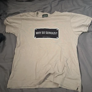 Beige t-shirt från John Hatter & Co pris kan diskuteras - Snygg beige t-shirt från John Hatter & Co med texten 'Why So Serious?' tryckt på framsidan. Perfekt för en avslappnad stil.