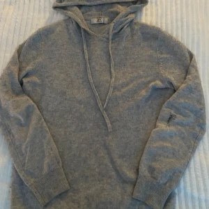 Kashmir hoodie grå - Säljer en stilren grå kashmir hoodie från BVALDI. Perfekt inför våren och sommaren. Den har ett liten skada på vänstra armen men går att sy ihop. Kontakta mig om du är intresserad. (Det går att buda ner i pris pga skadan