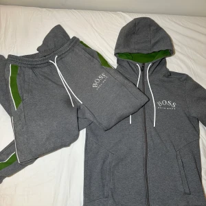 Grå Hugo Boss Tracksuit/ Dress - OBS! Den mörka fläcken på bilden är endast på min kamera!! Dressen är alltså inte fläckig. Skicket är som nytt.  Storlek S. Byxorna är raka, så de lägger sig riktigt snyggt över dina skor. Tveka inte på att höra av dig om du har minsta fråga eller fundering, jag svarar snabbt 💯💪