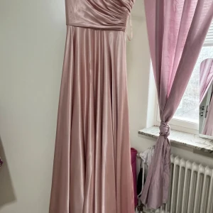 Rosa axelbandslös långklänning - Elegant rosa långklänning i satin med axelbandslös design.Klänningen har en snörning i ryggen för passformen. Jag hade den på mig en gång men vill inte ha den längre. Köptes för 3100kr. Priset kan diskuteras 