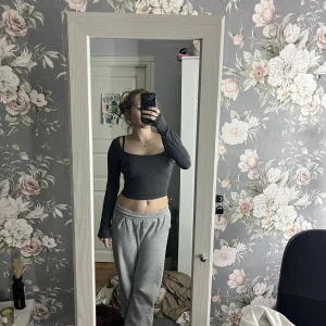 Mörk grå långärmad croppad topp - Snygg grå långärmad croppad topp med en stilren design. Perfekt för en trendig look.