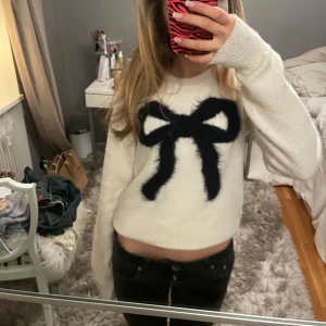 Vit tröja med svart rosett - Säljer en söt vit tröja med en stor svart rosett på framsidan använd typ 3 gånger så jätte bra skick