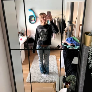 Svart långärmad tröja med tryck - Säljer en svart långärmad tröja med ett coolt vintage-tryck på framsidan. Perfekt för en avslappnad stil. Tröjan har en normal passform och är gjord i ett mjukt material.