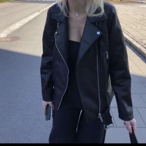 Svart skinnjacka från Vero Moda - Snygg svart skinnjacka från Vero Moda med dragkedja och klassisk bikerstil. Perfekt för en cool och stilren look. Jackan har långa ärmar och en asymmetrisk dragkedja framtill.priset kan diskuteras!❤️oversized