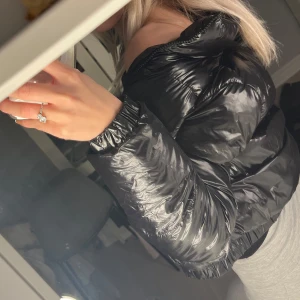 Svart pufferjacka - Jätte snygg svart pufferjacka med dragkedja. Jackan har en glansig yta och är perfekt för kyligare dagar då den är sjukt varm. Den har långa ärmar och en croppad passform som ger en modern look. 😍😍🥰🥰🥰 som ny inte använd nypris är 679 säljer för 400