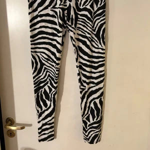 Zebramönstrade leggings - Snygga zebramönstrade leggings i svart och vitt. Perfekta för att sticka ut med ett djärvt mönster. De har en tight passform och är gjorda i ett stretchigt material för extra komfort. Viskostrikå.