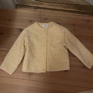 Gul och vit mönstrad jacka från Zara - Säljer en söt gul och vit mönstrad jacka från Zara. Jackan har en kort passform med långa ärmar och knappar framtill. Perfekt för vår och sommar!